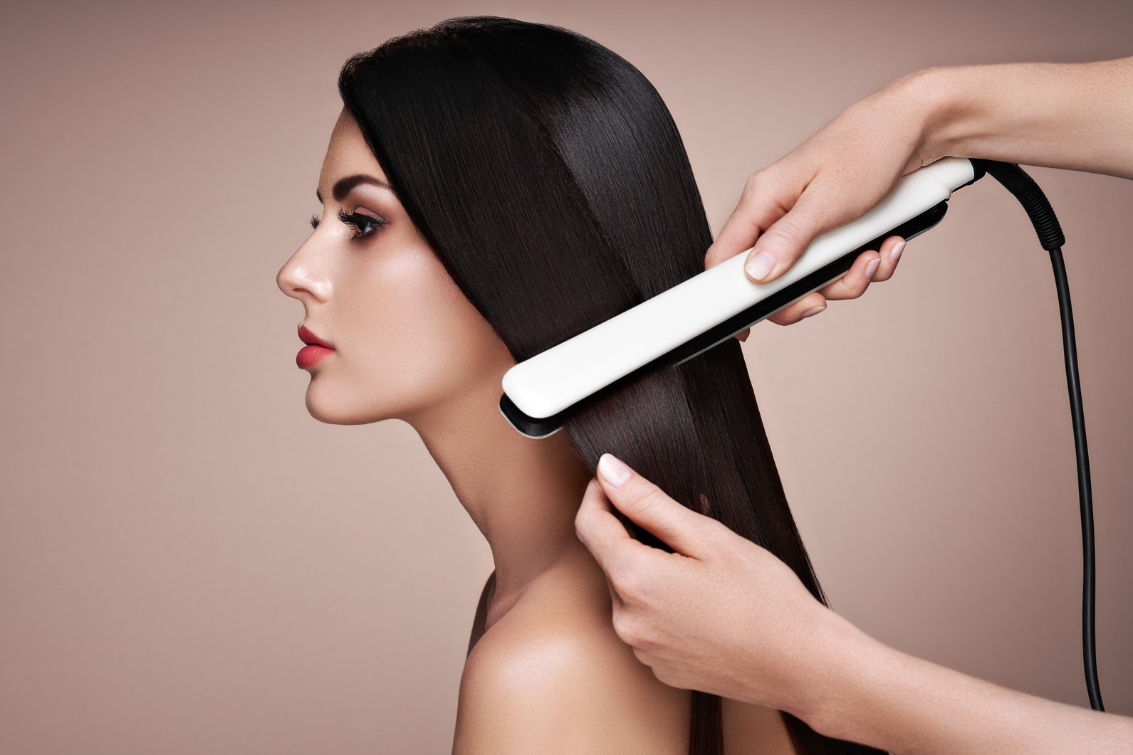 Hairdresser straightening long hair with hair irons